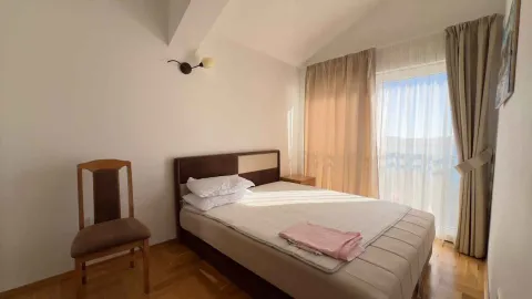 Spavaća soba sa bračnim krevetom, drvenom stolicom i balkonskim vratima. - image 6