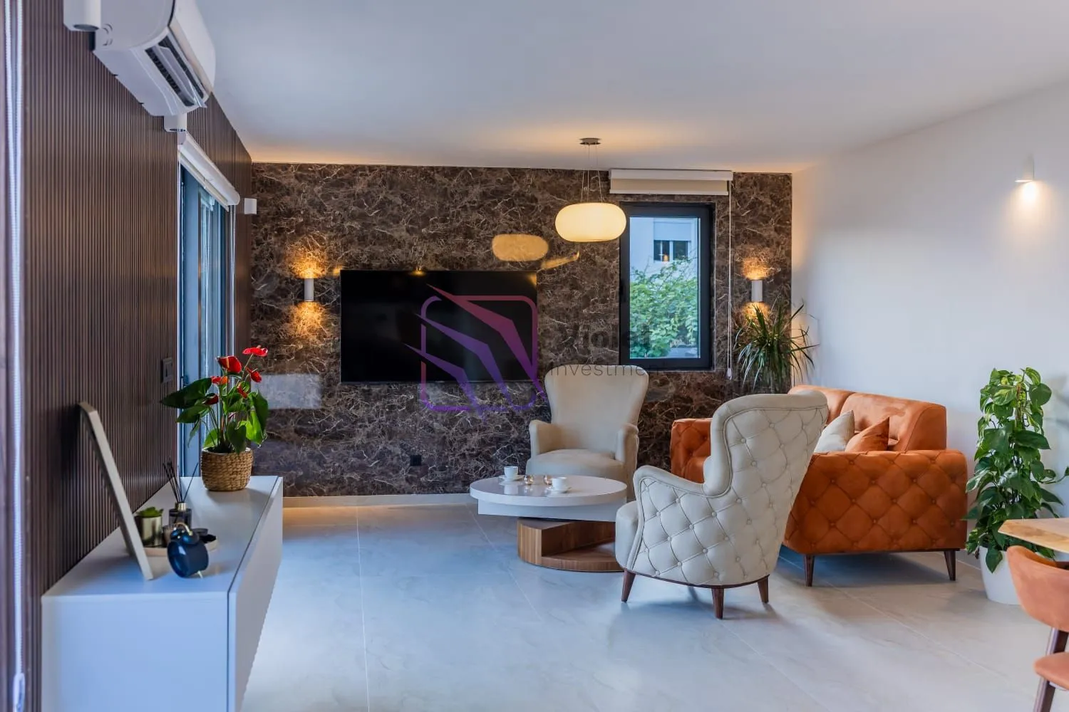 Living room with a sofa, armchairs, TV, and a decorative wall.
