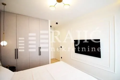Modern bedroom with built-in wardrobes, a double bed, and a wall-mounted TV.