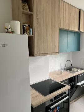 Small kitchen with wooden cabinetry, built-in oven, and refrigerator. - image 6