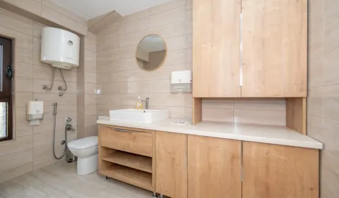 Tiled bathroom with a washbasin, toilet, and wooden cabinetry. - image 10
