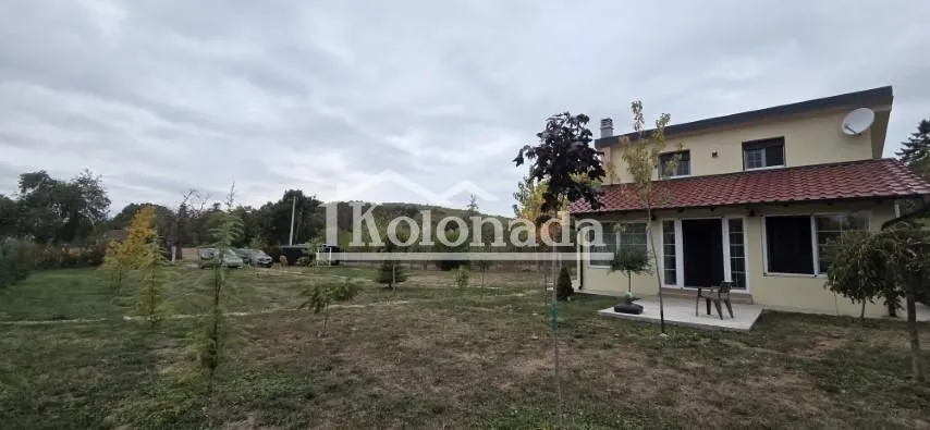 Pogled na dvorište i fasadu kuće sa uređenom travnatom površinom.