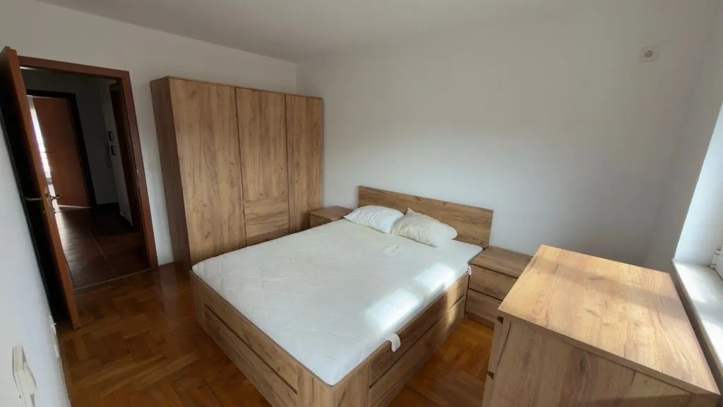 Bedroom with a double bed, wooden wardrobe, and dresser.
