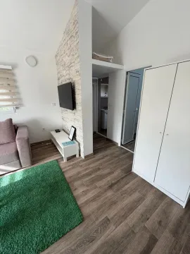 Living room with a sofa, TV, and white wardrobe. - image 4