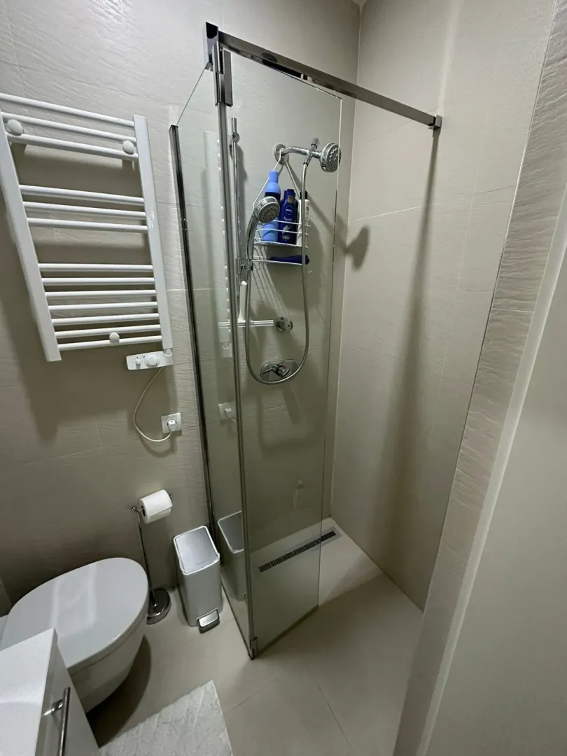 Kupatilo opremljeno tuš kabinom, WC šoljom i radijatorom za peškire.