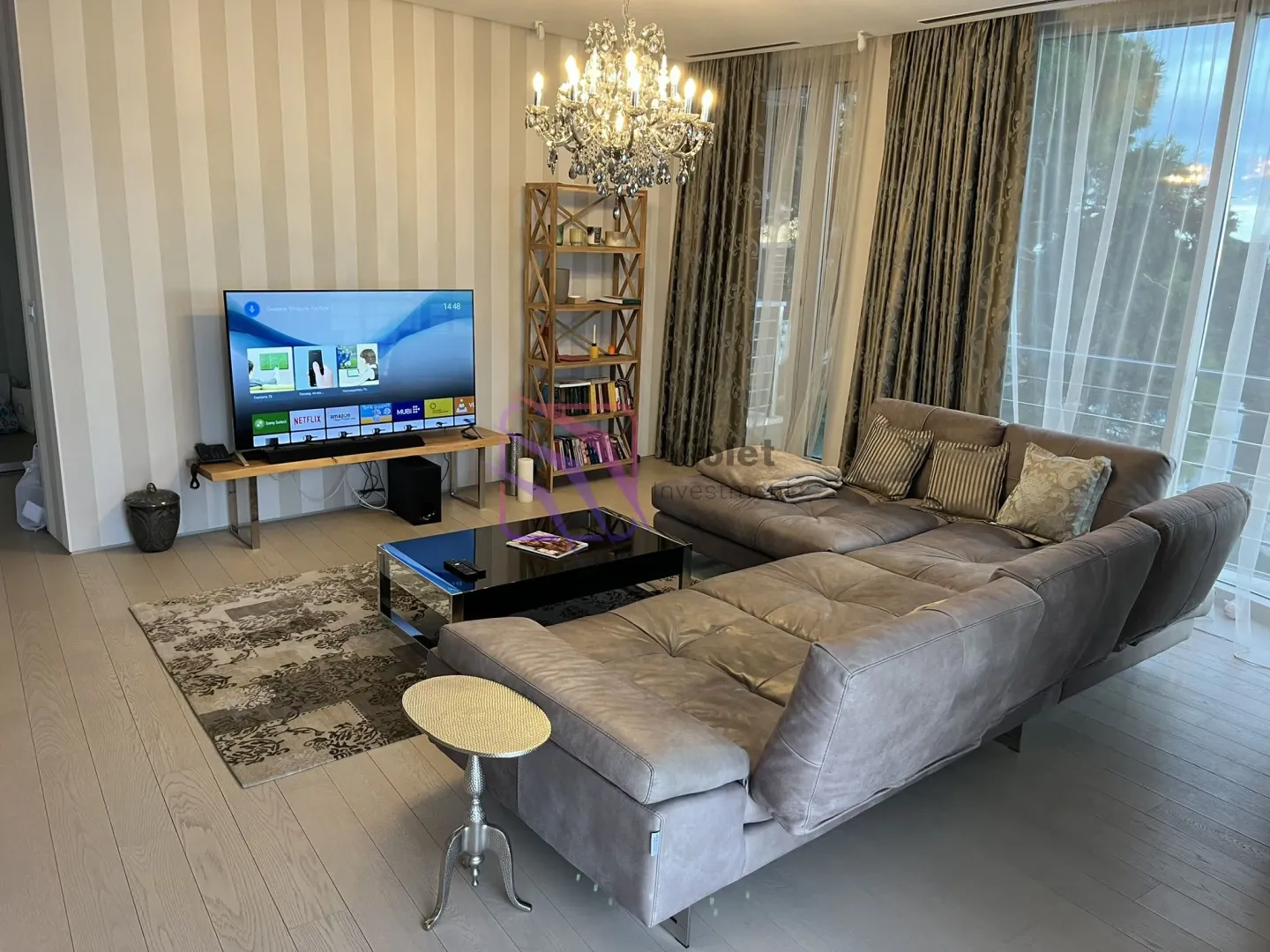 Spacious living room with a sectional sofa, TV, and access to the terrace.