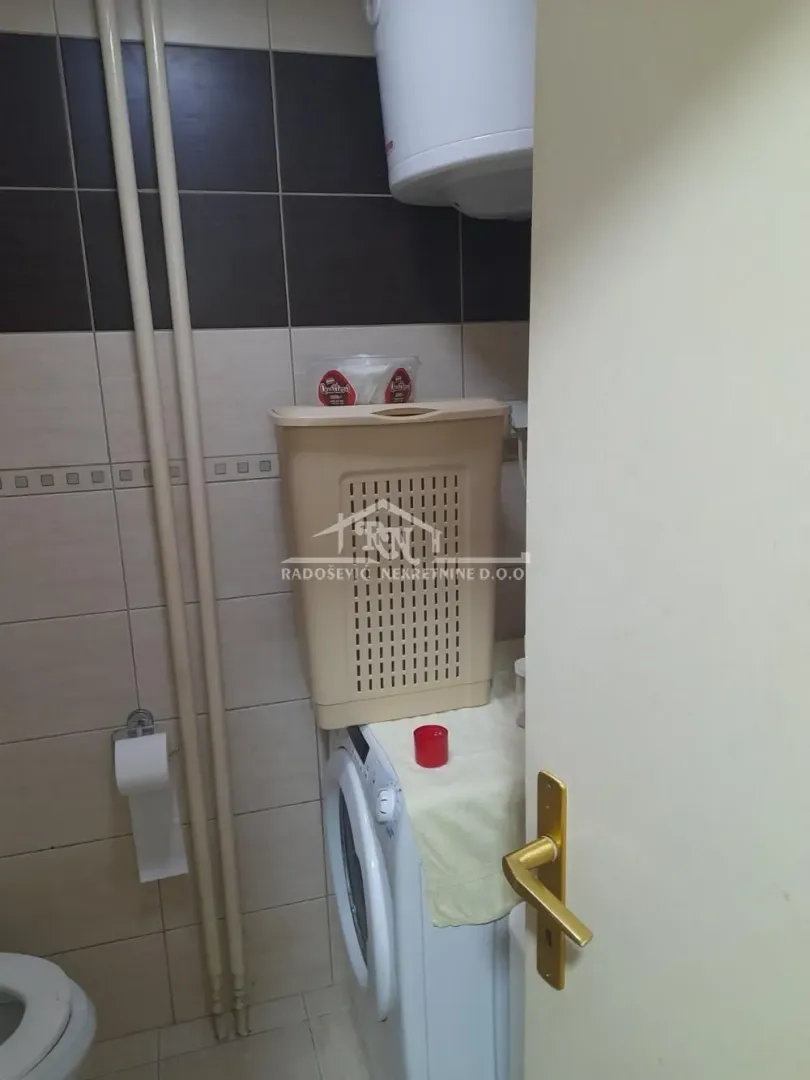 View of the bathroom with a washing machine and a laundry basket.
