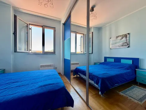 Spavaća soba sa plavim krevetom i velikim ugradnim ormarom sa ogledalom. - image 6