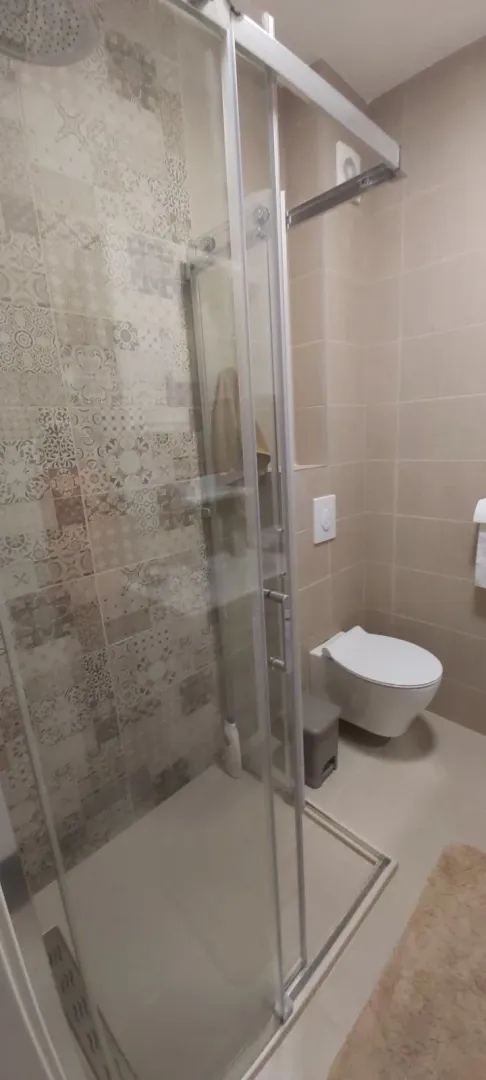 Moderno opremljeno kupatilo sa tuš kabinom i WC šoljom.