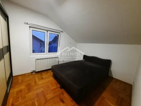 Attic bedroom with a double bed, wooden parquet flooring, and a window. - image 7