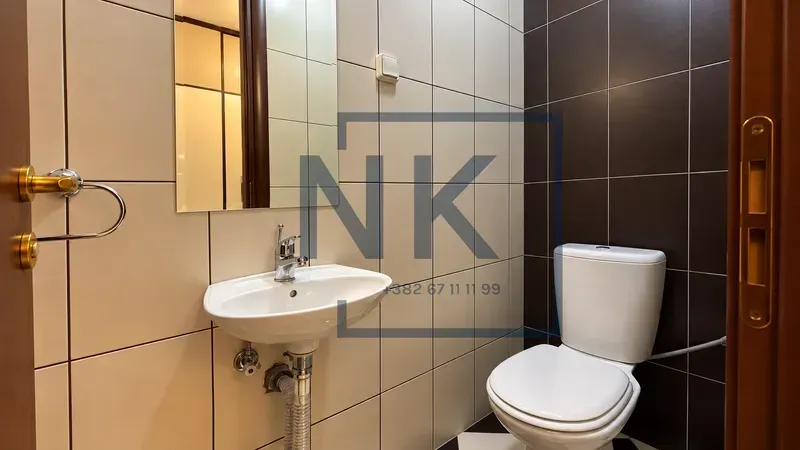 Small bathroom with a sink and toilet tiled with ceramic tiles.