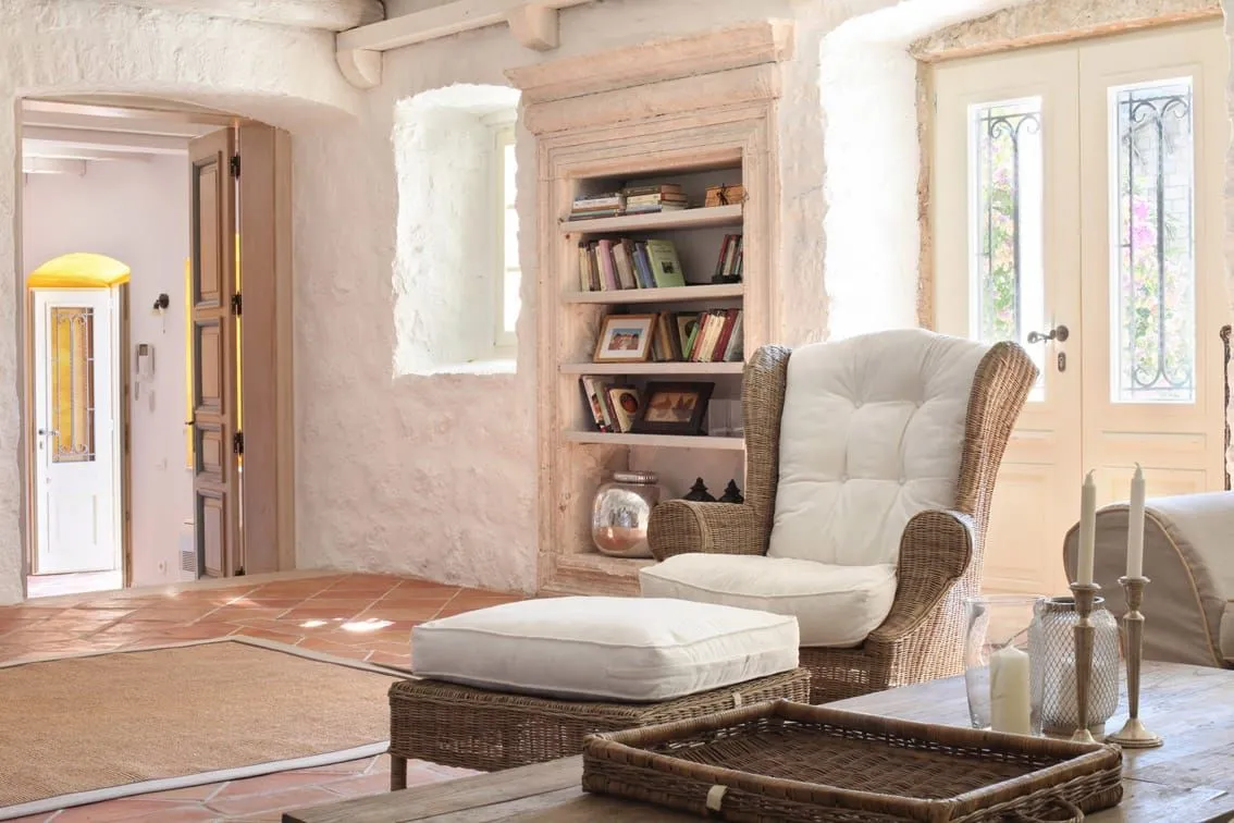 Living room with rustic stone walls, a wicker armchair, and wooden furniture.