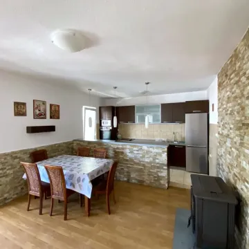 Kitchen with dining area furnished with dark cabinets, wooden table, and wood-burning stove. - image 6