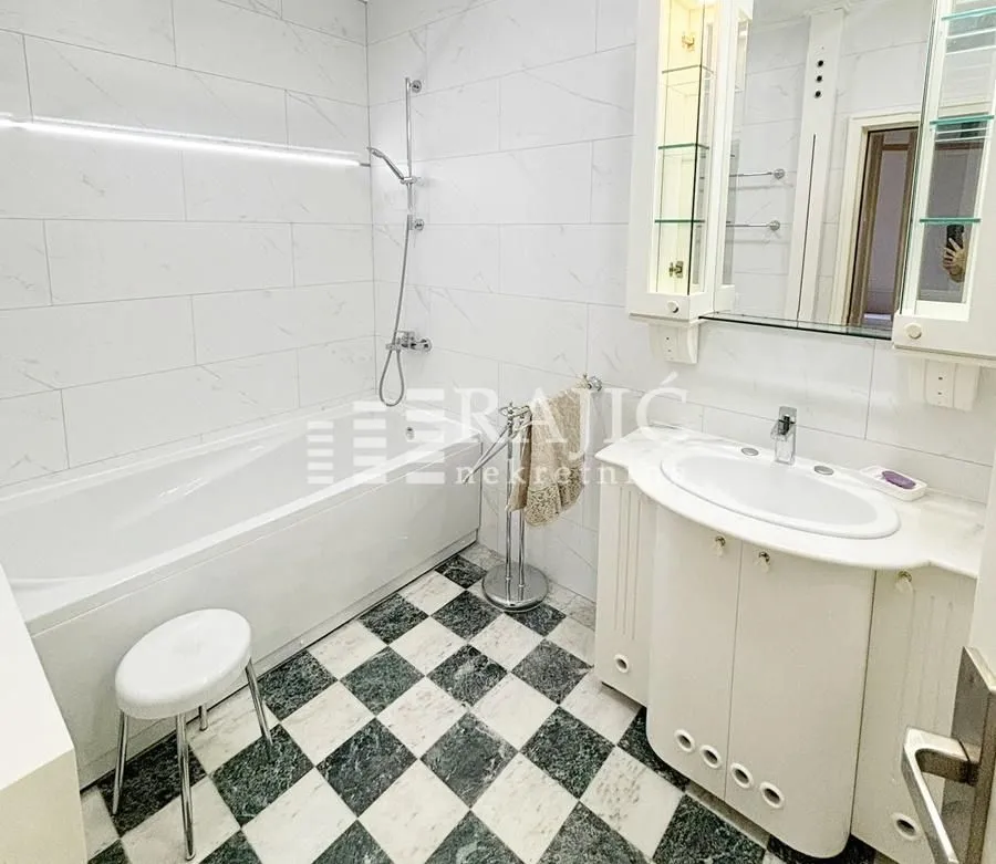 Bright bathroom with a bathtub, sink, and white tiles.