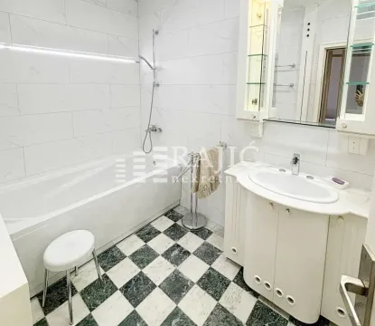 Bright bathroom with a bathtub, sink, and white tiles. - image 10