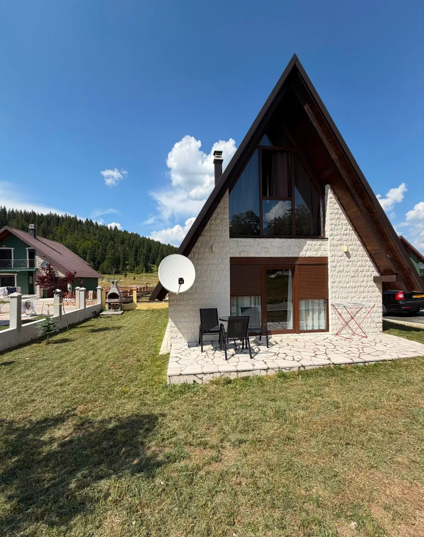 Pogled na fasadu i dvorište vikendice sa terasom i prostorom za sjedenje.