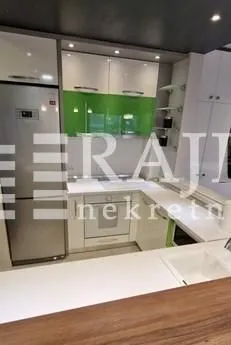 Moderna kuhinja sa belim i zelenim elementima i ugrađenim frižiderom. - image 6