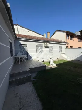 Dvorište kuće sa popločanom terasom, travnjakom i stolom sa stolicama. - image 8