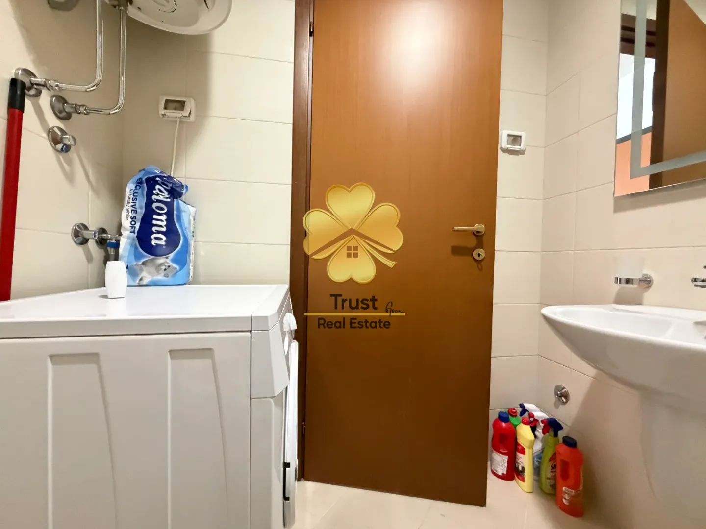 Small bathroom with a washing machine, washbasin, and a door.