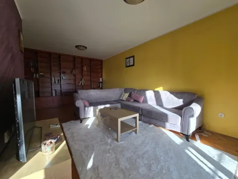 Spacious living room with a sectional sofa, a large bookcase, and a yellow wall. - image 2