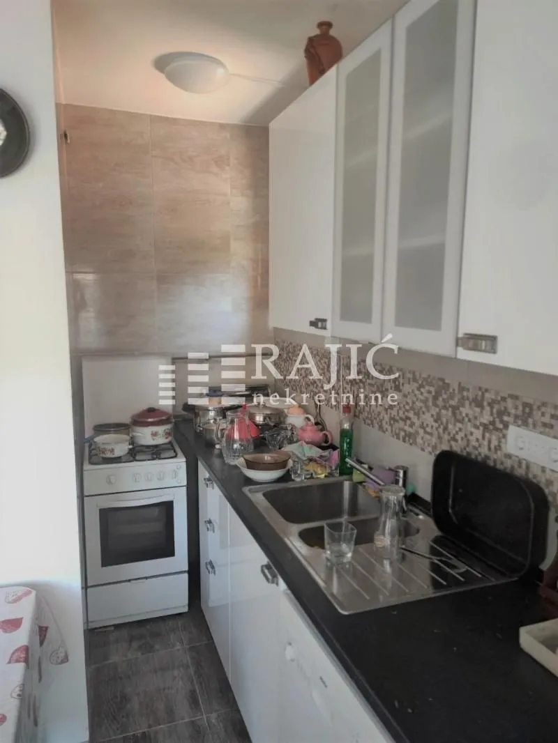 Small kitchen with white cabinets and dishes on the countertop.