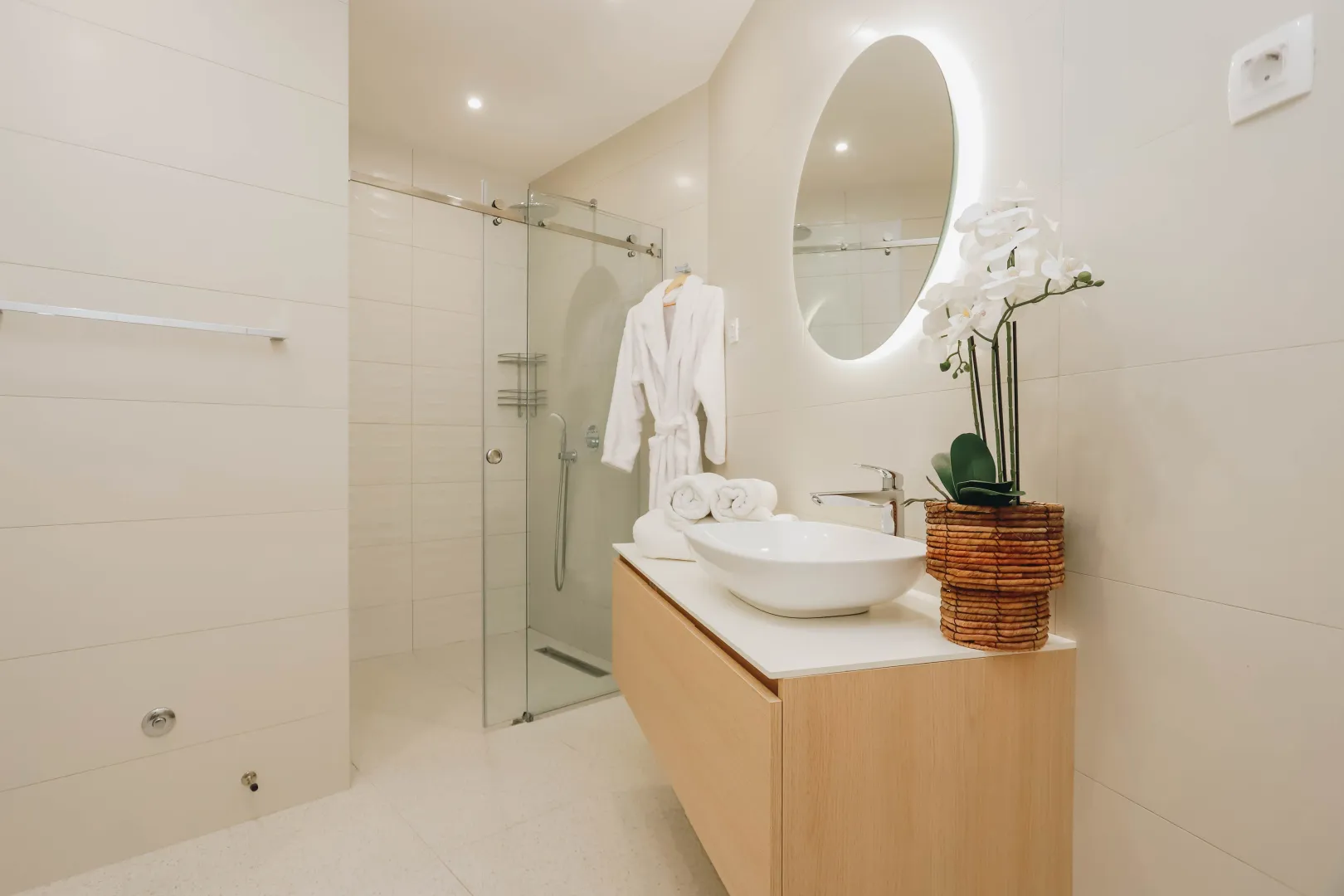 Modernly equipped bathroom with a walk-in shower, washbasin, and mirror.
