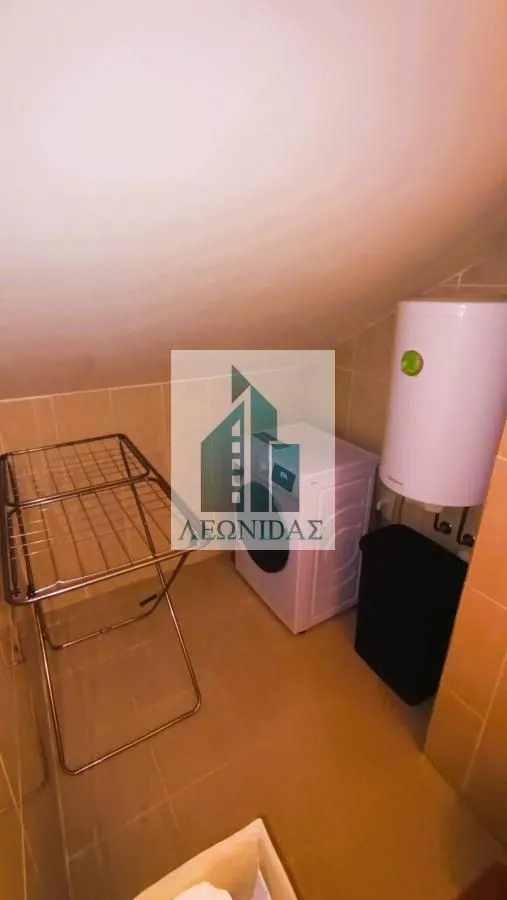 Small bathroom with a washing machine, water heater, and a drying rack.