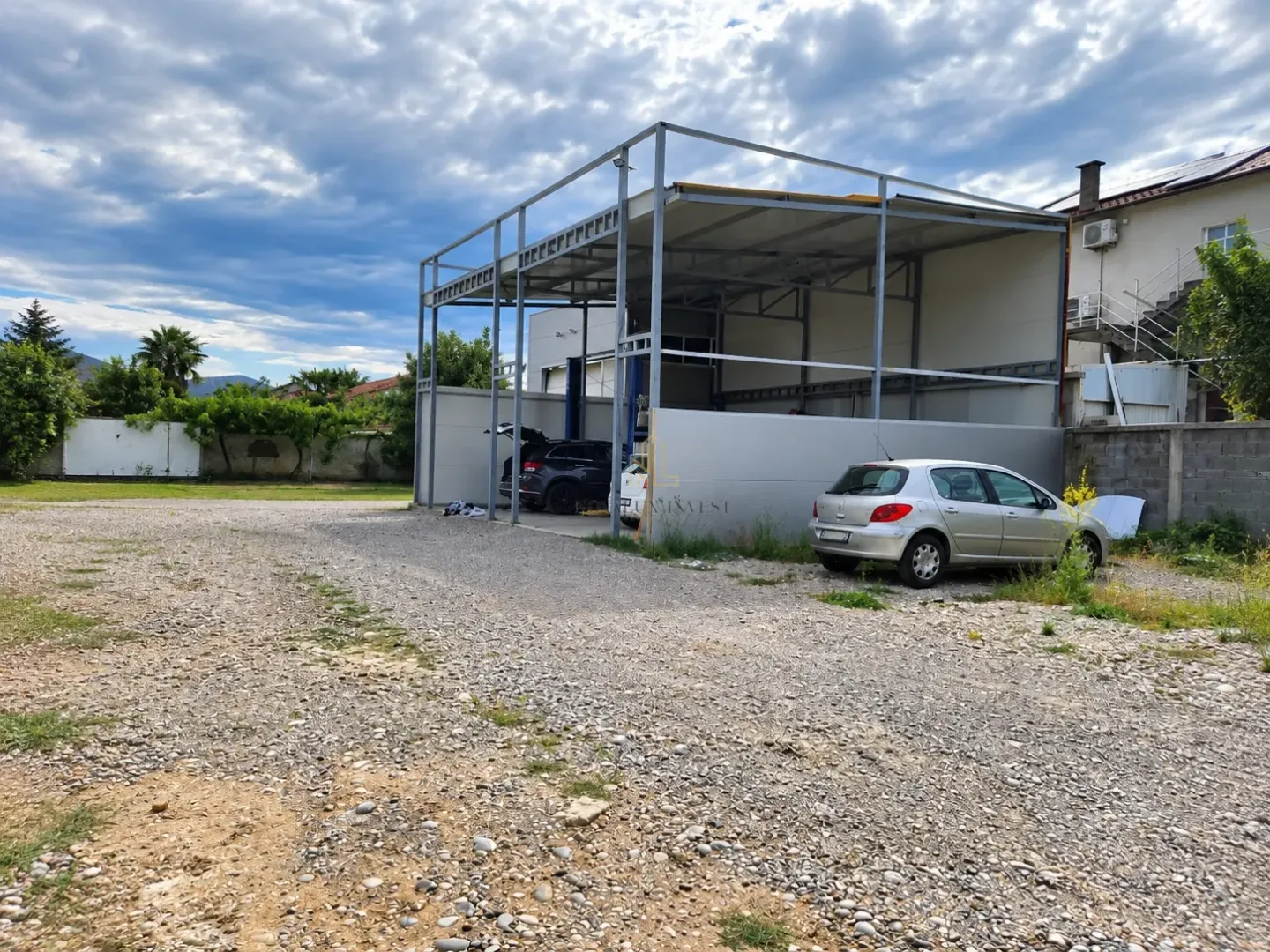 View of the yard with a metal auxiliary structure and parked cars.