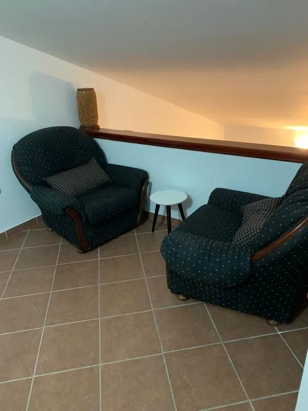 Small seating area with armchairs on a tiled gallery.