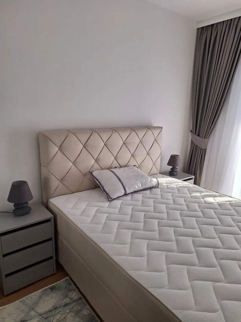 Svijetla spavaća soba sa modernim bračnim krevetom i noćnim stočićima.
