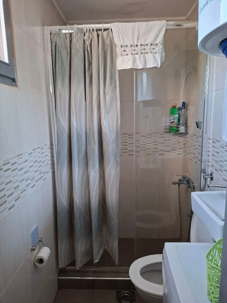 Small bathroom with a shower cabin, sink, and washing machine.