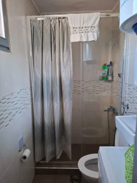 Small bathroom with a shower cabin, sink, and washing machine. - image 9