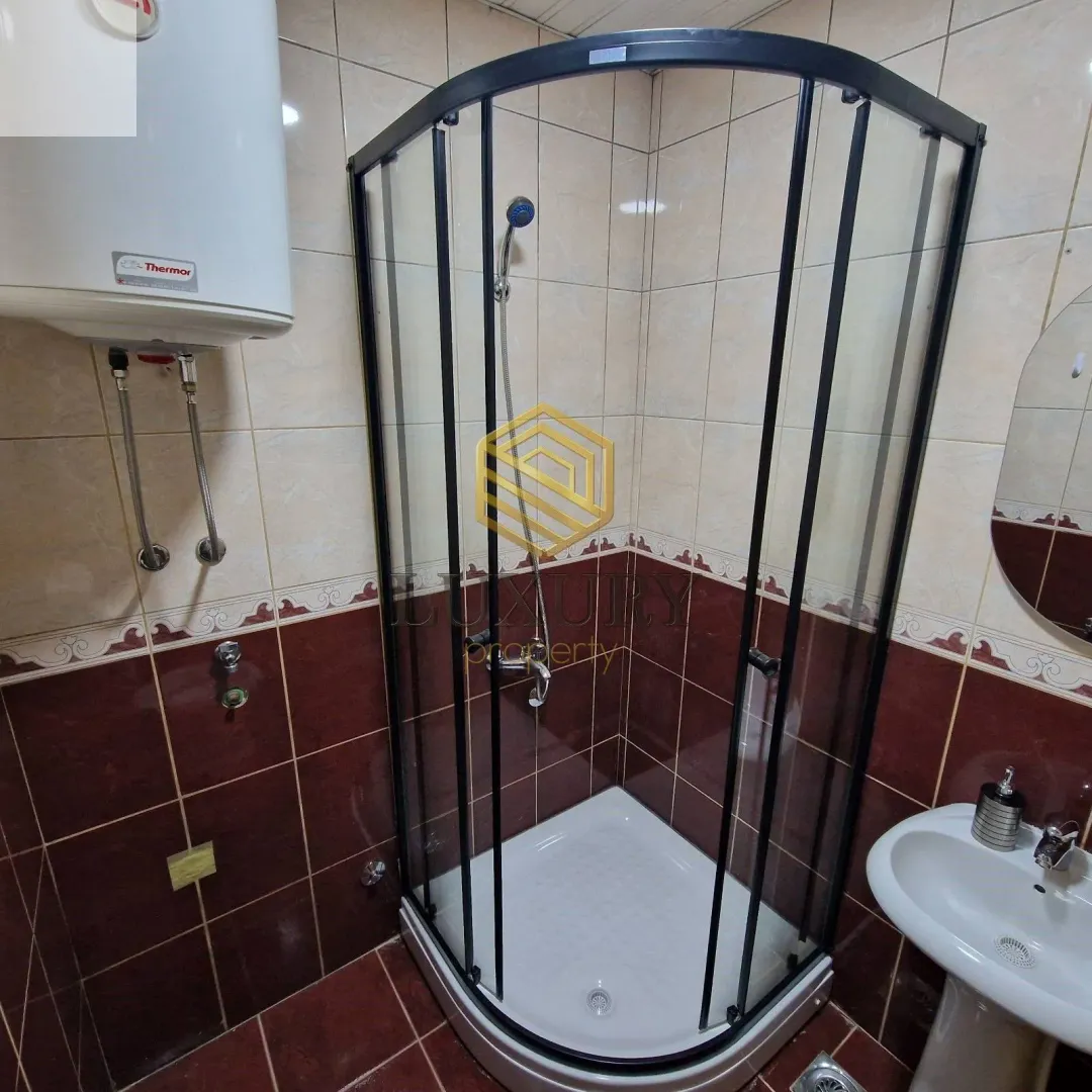 Smaller bathroom with a shower cabin, sink, and water heater.