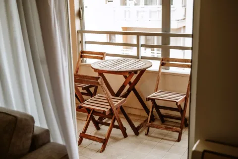 A balcony with a wooden seating set. - image 16