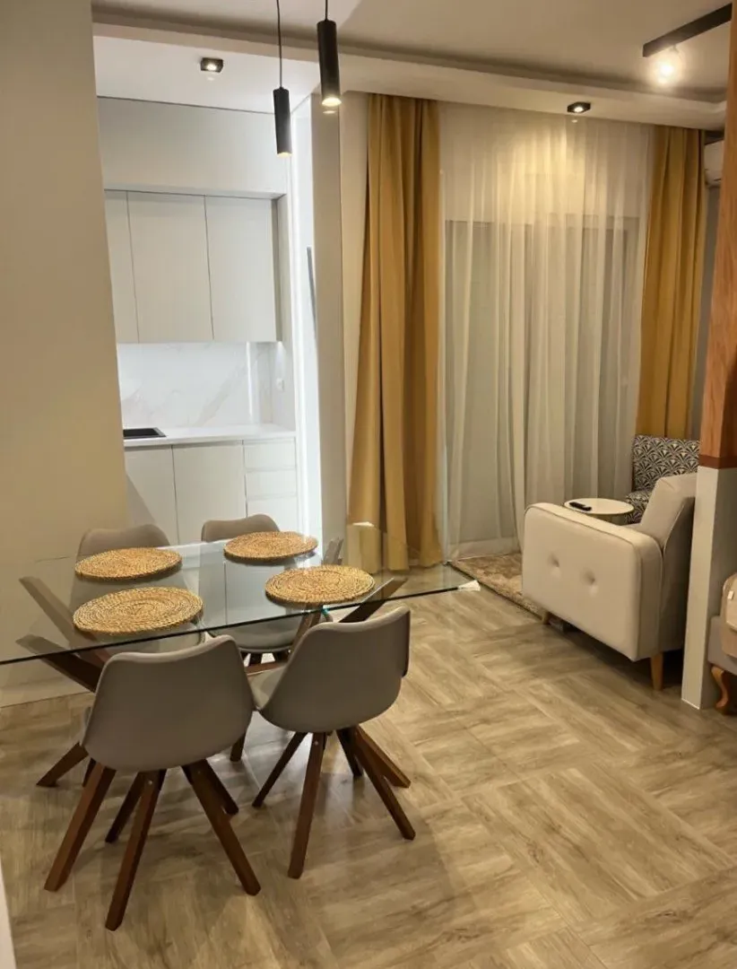 Modern living room with a dining area and a built-in kitchen in the background.