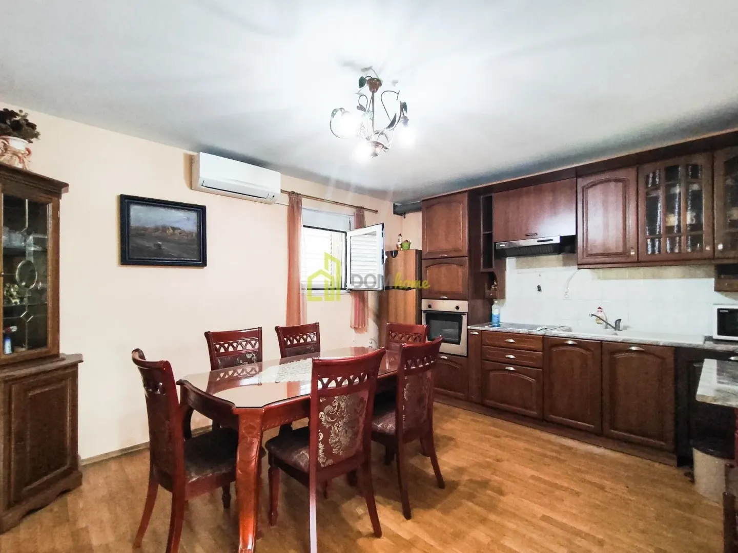 Dining area with a wooden table and chairs connected to a dark-toned kitchen.