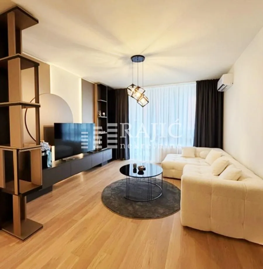 Living room with a sofa, TV, and shelving unit.