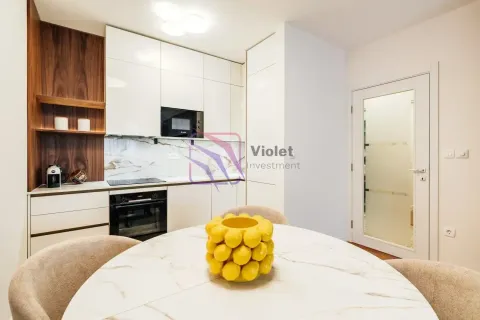 Moderna kuhinja sa bijelim elementima i trpezarijskim stolom u prvom planu. - image 3
