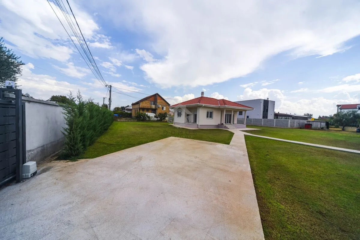 View of the courtyard and driveway of a family house with a lawn.