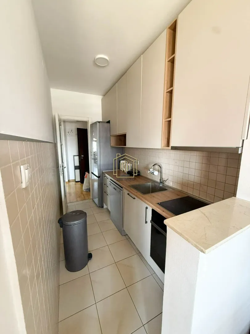 Small kitchen with white cabinetry, built-in appliances, and a refrigerator.