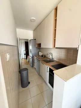 Small kitchen with white cabinetry, built-in appliances, and a refrigerator. - image 11