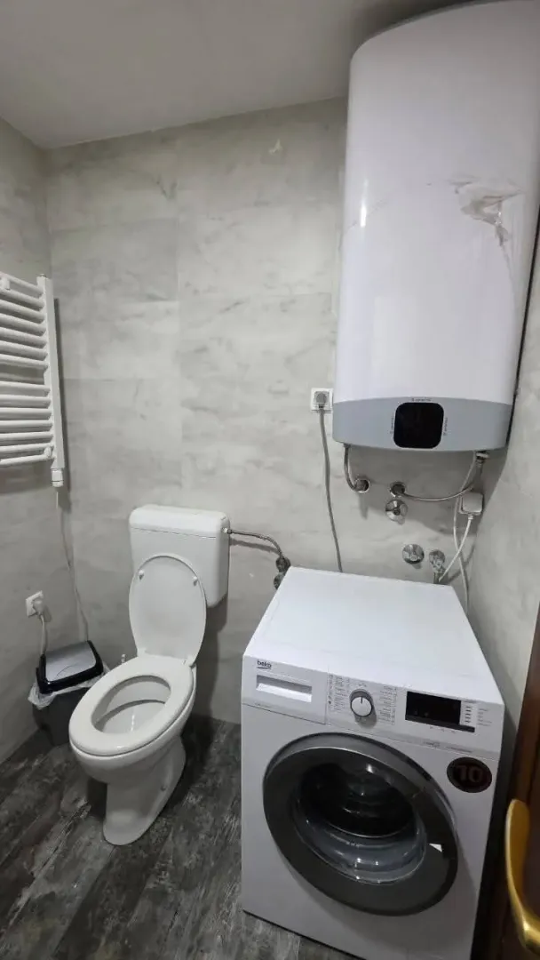 Manje kupatilo sa toaletom, veš mašinom i bojlerom.
