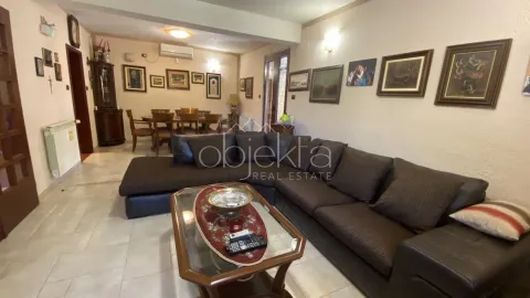 Living room with a sofa, coffee table, and dining area in the background. - image 10