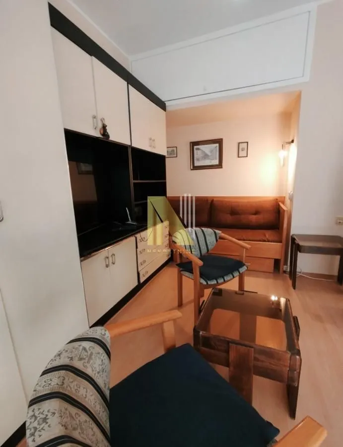 Manja dnevna soba sa garniturom za sedenje i drvenim nameštajem.