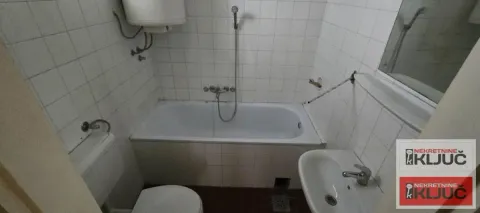 Manje kupatilo sa kadom, umivaonikom i toaletom obloženo belim pločicama. - image 8