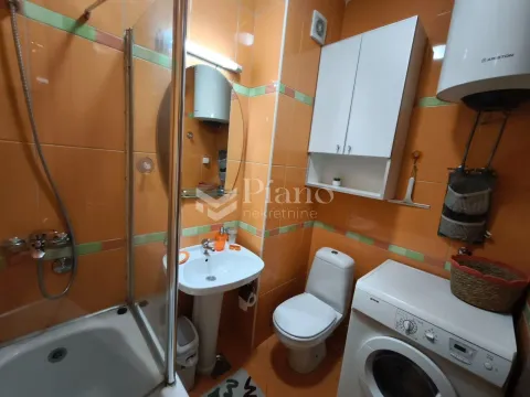 Kupatilo sa narandžastim pločicama, tuš kabinom, umivaonikom, WC šoljom i veš mašinom. - image 9