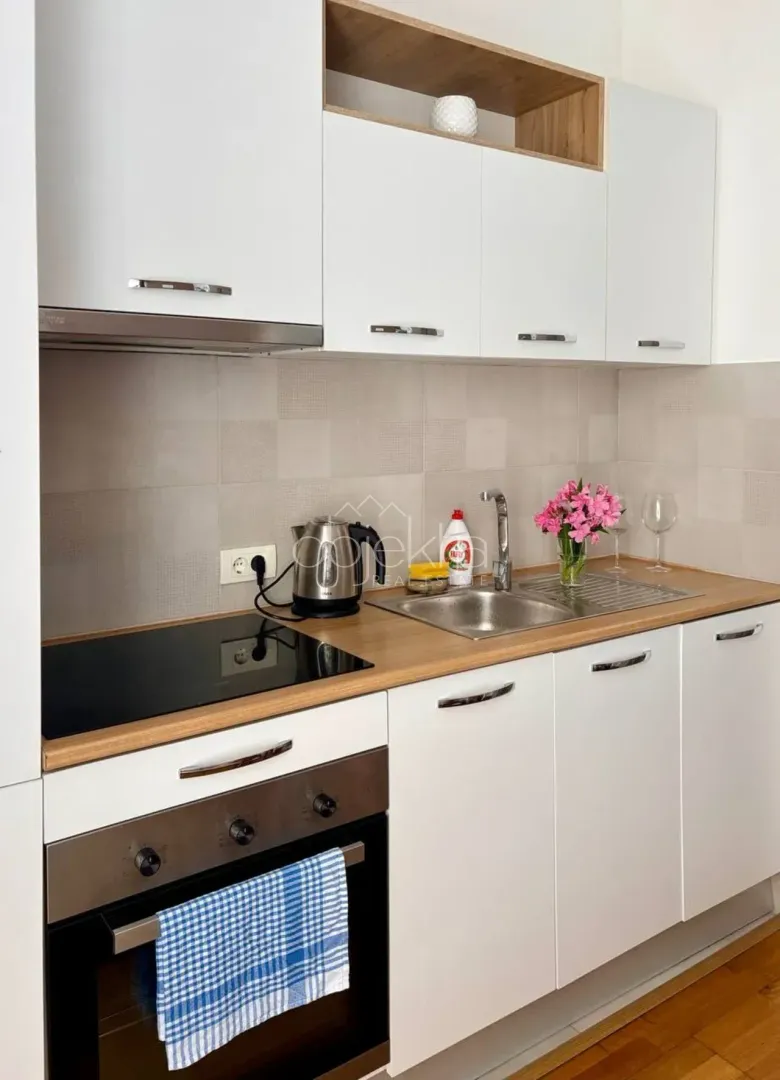 Small kitchen with white cabinets, built-in oven, and cooktop.