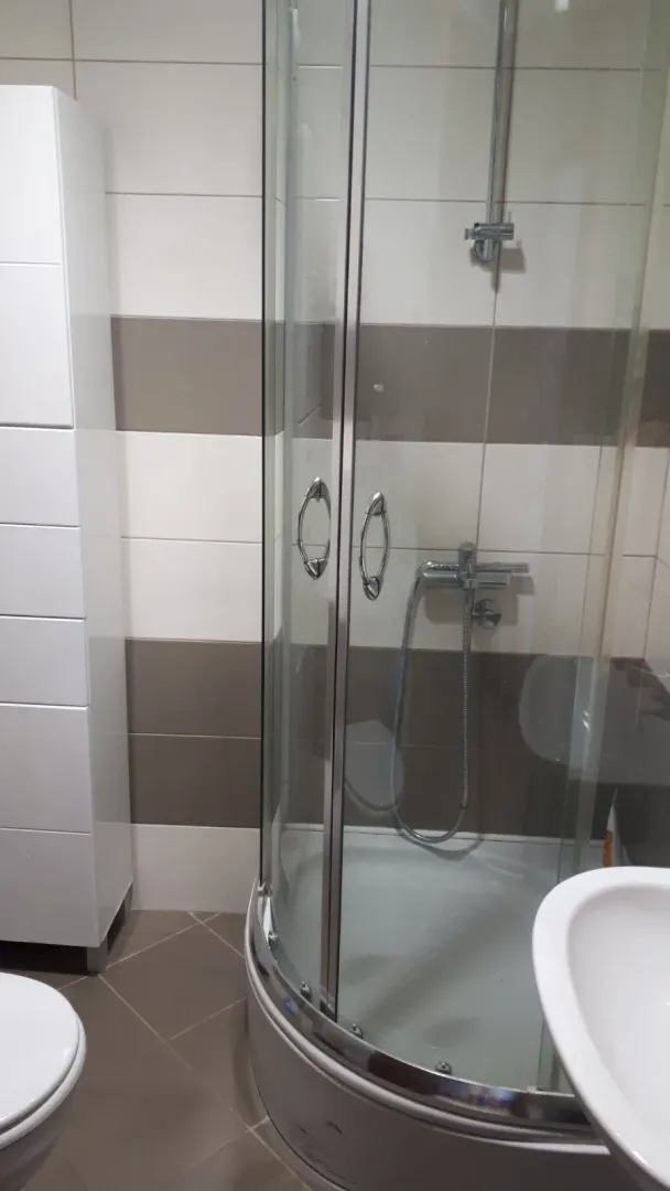 Small bathroom with a shower cabin, washbasin, and white storage units.