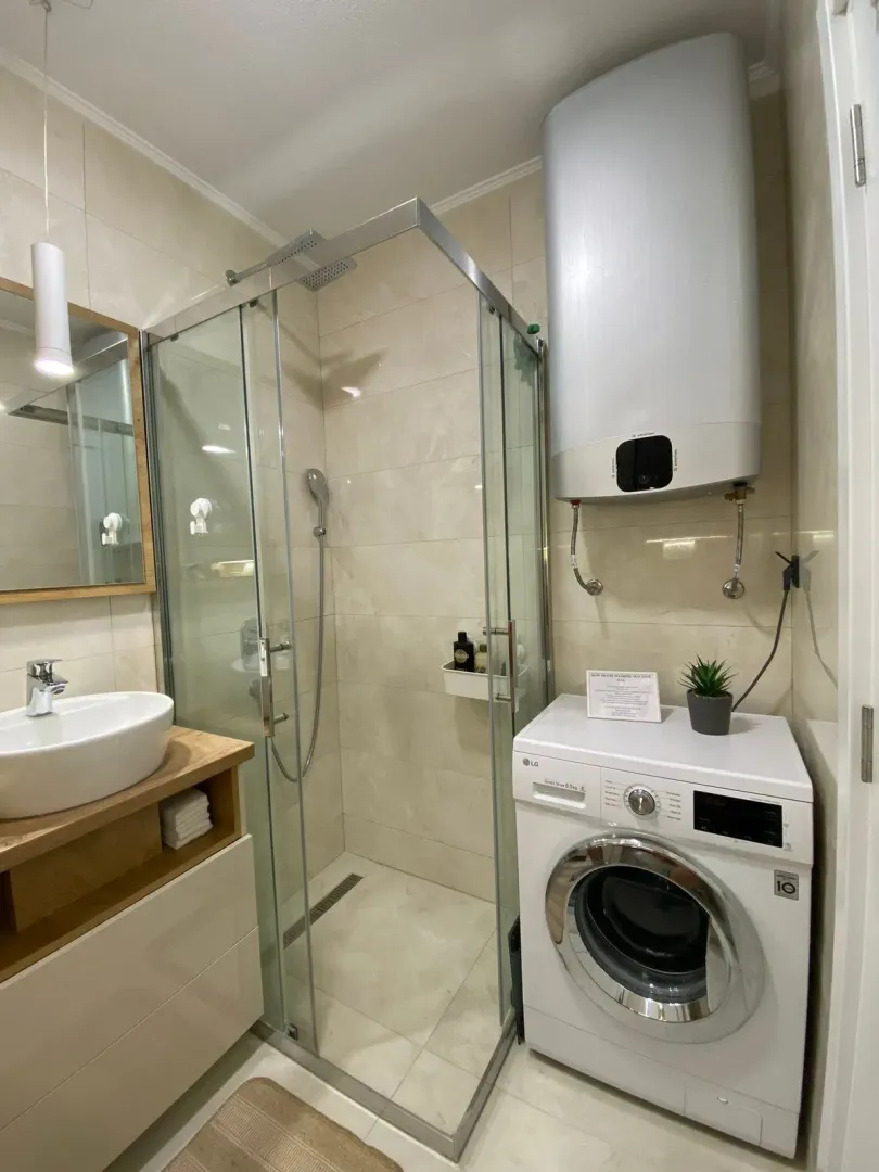 Bathroom with a shower cabin, washbasin, and washing machine.