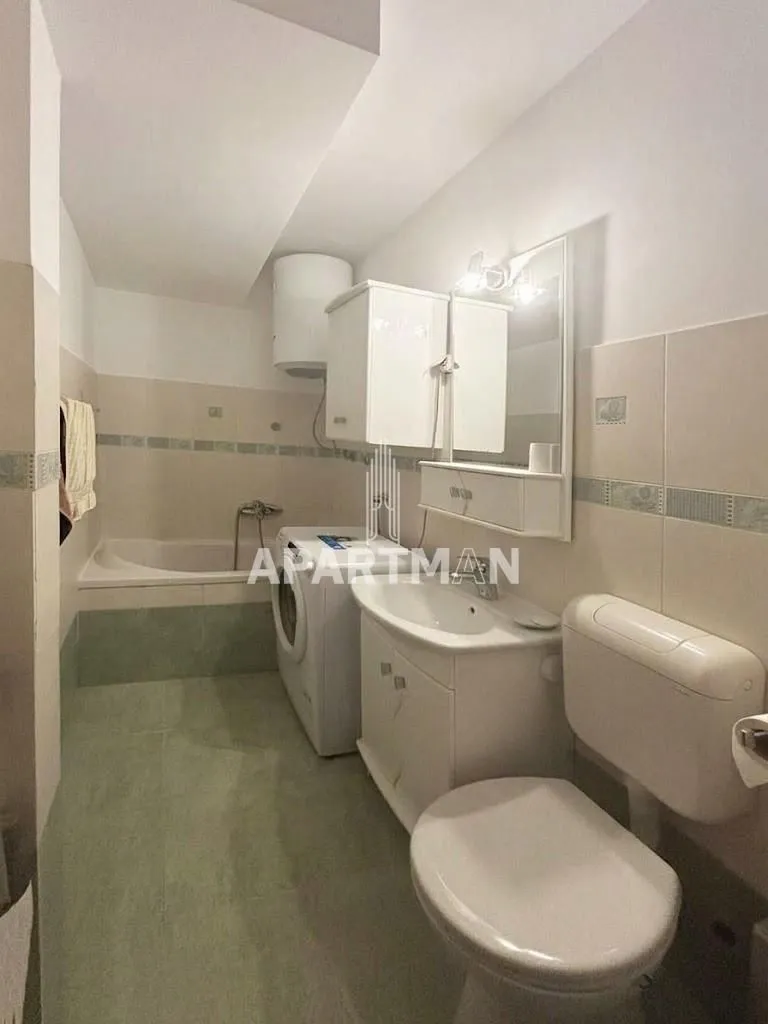Kupatilo opremljeno sanitarijama, kadom i mašinom za veš.